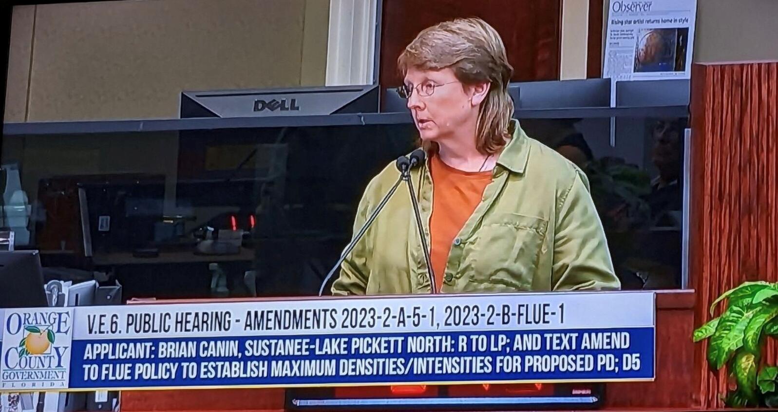 A screenshot of a televised county commission meeting where a woman is speaking.