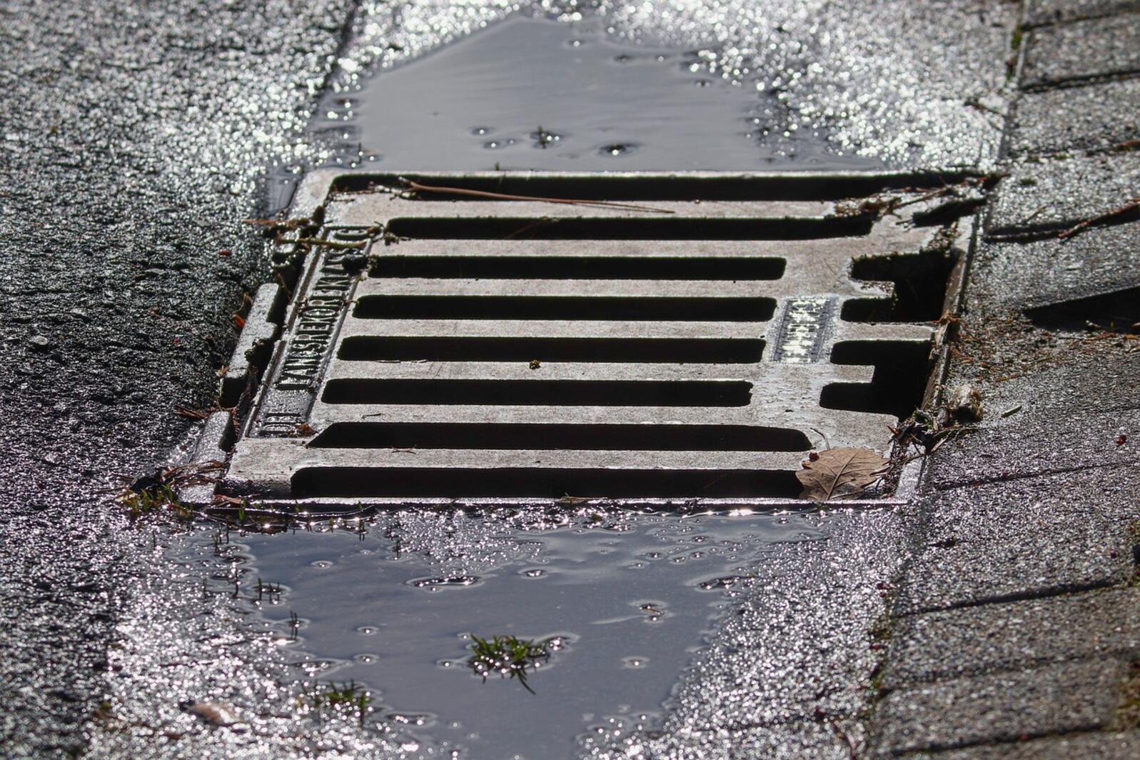 water flowing into a drainage grate in the pavement.