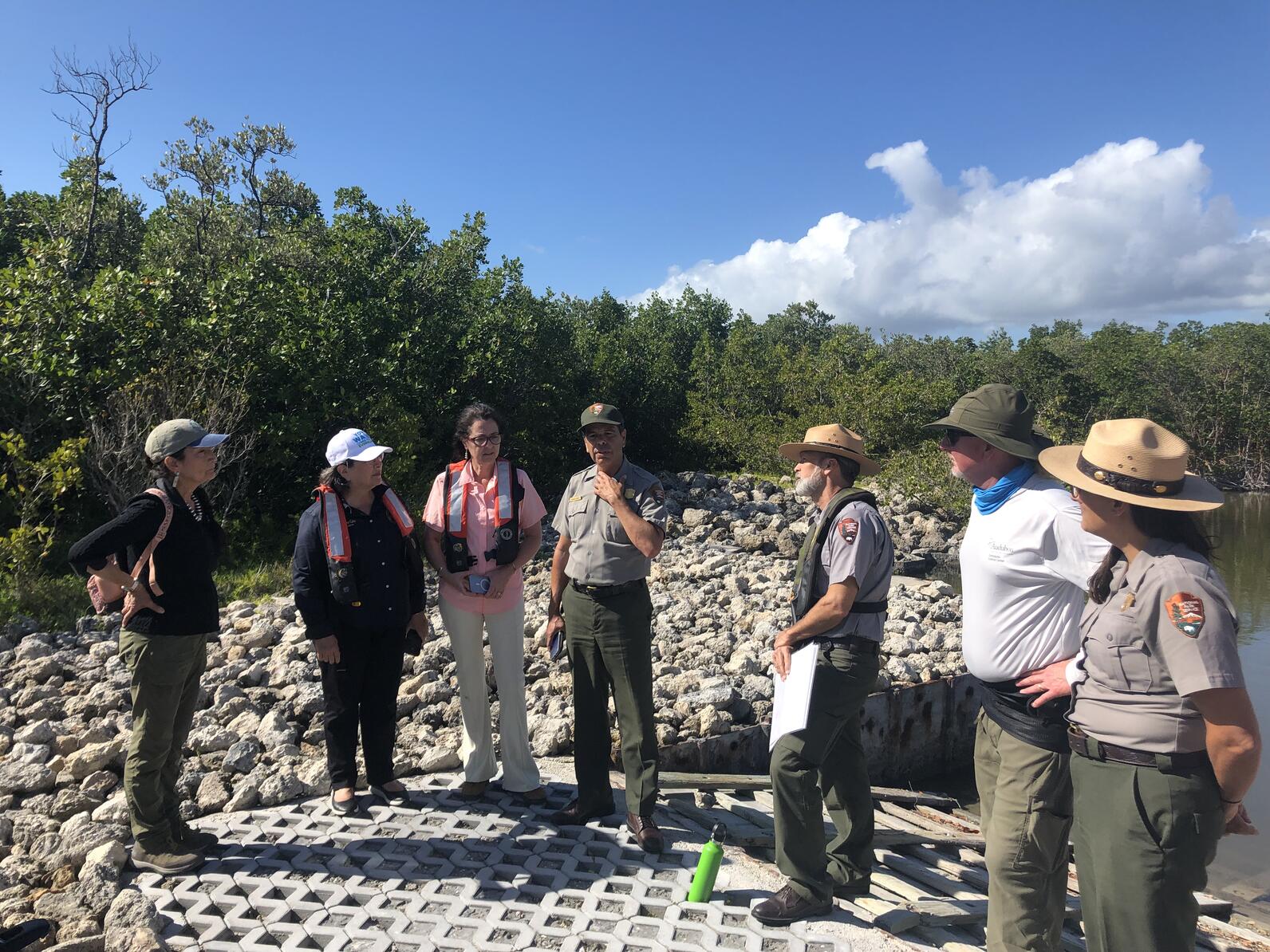 Field trip participants listen to Everglades National Park staff, standing on land.