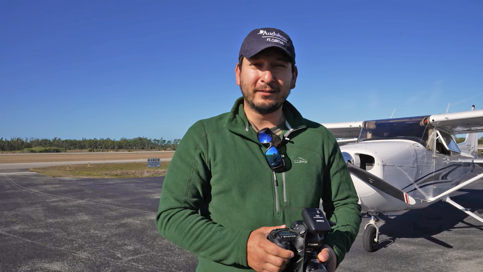 A man holding a camera standing in front of an airplane