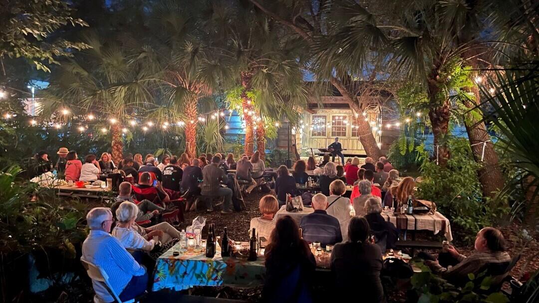 Attendees enjoy an outdoor evening performance at Tropical Audubon Society's Birdstock event at the historic Doc Thomas House.