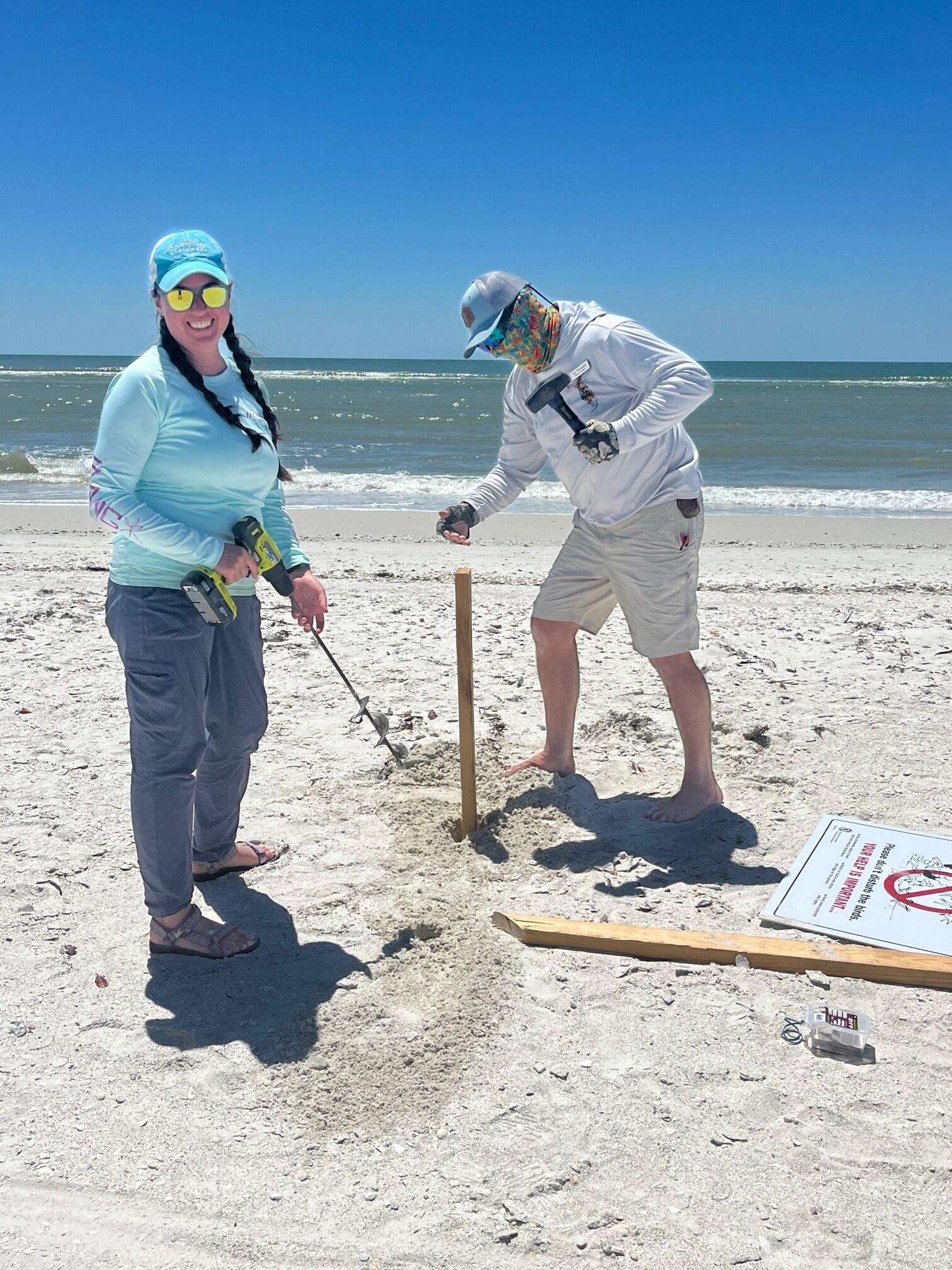 Two people putting up signs at the beach