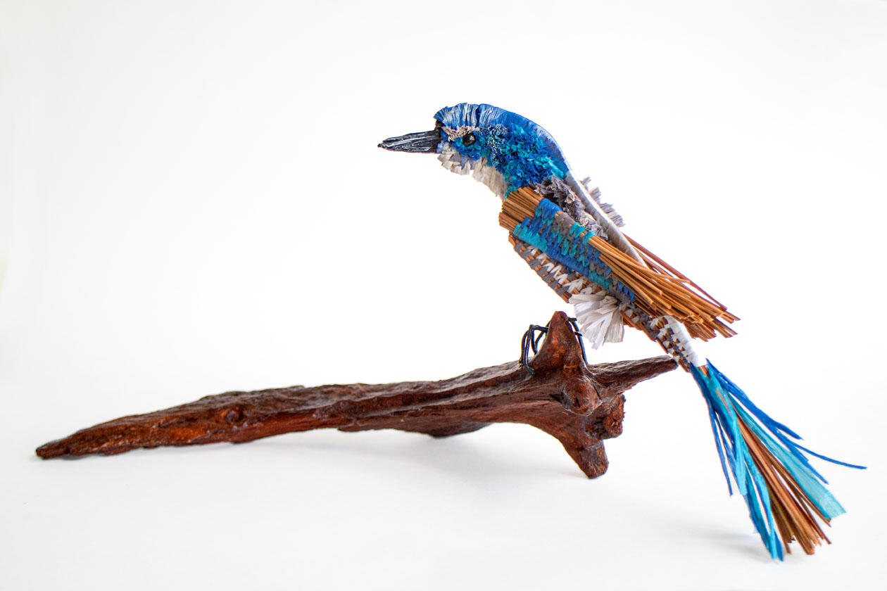 Pine needle sculpture depicting a Florida Scrub-Jay, sitting on a piece of driftwood. 