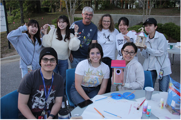 Students sitting around a table, smiling at the camera.